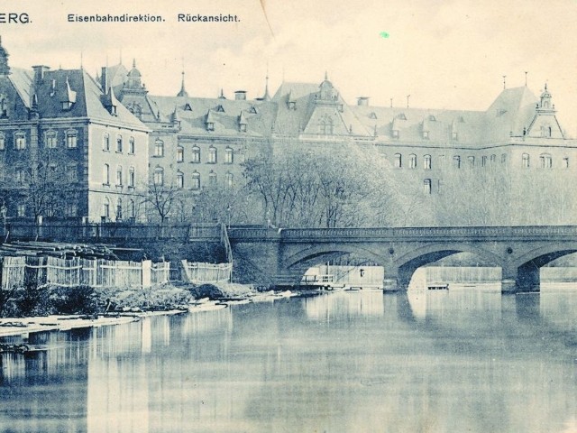 Za trzyprzęsłowym mostem widać okazały gmach dyrekcji kolejowej. Wybudowano go w latach 1886-1889.