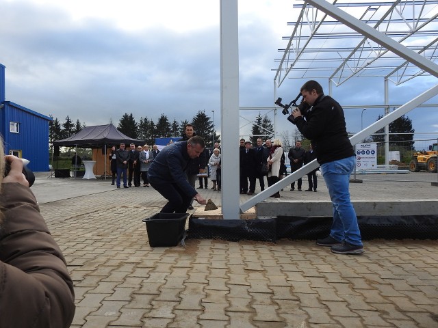 Leszek Gołąbiecki, prezes spółki Unibep, wmurowuje kamień węgielny, za nim Roman Jakubowski, dyrektor oddziału Unihause