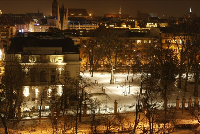 Nowe oświetlenie parku Staromiejskiego na tle starego, żółtego oświetlenia ulicznego w centrum