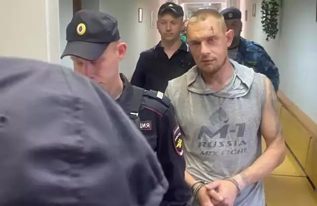POlicjanci prowadzą 37-letniego Igora Sofonowa na przesłuchanie.