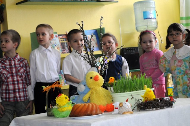 Przedszkolaki z tarnobrzeskiej "siedemnastki&#8221; układały na stole symbole Świąt Wielkanocnych, takie jak pieczona babka, sól, baranek oraz kurczaczek.
