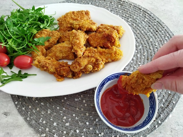 Chrupiące kawałki kurczaka pysznie smakują np.  z ketchupem, sosem czosnkowym lub pomidorową salsą.