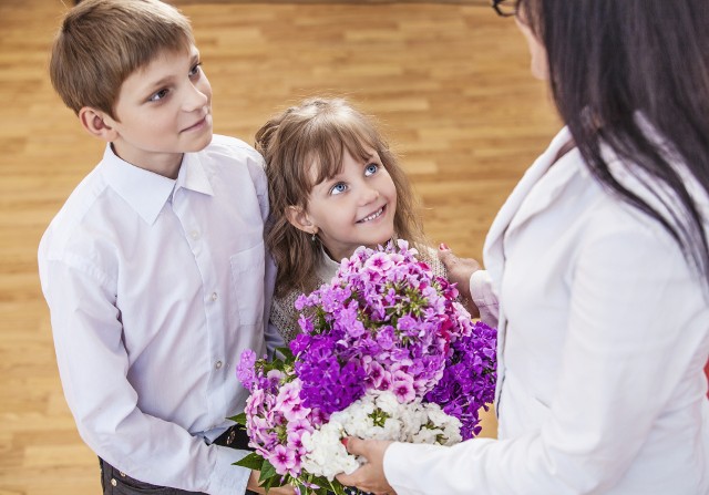 Uczniowie wręczają nauczycielce kwiaty z okazji Dnia Nauczyciela.