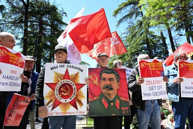 Gruzińscy komuniści z czerwonymi flagami i portretami Stalina podczas uroczystości Dnia Zwycięstwa na ulicach Tbilisi 9 maja 2023 roku.