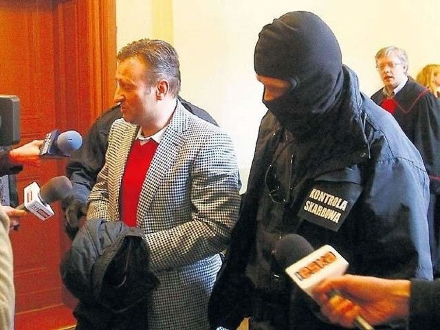 Prokurator Artur Maludy (z tyłu, z prawej) chwilę przed decyzją o aresztowaniu gastronomika Pawła G. (na zdjęciu konwojowany przez agentów).