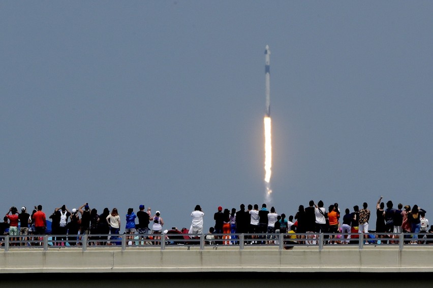 Ludzie oglądają start rakiety Falcon 9 z mostu w Titusville...