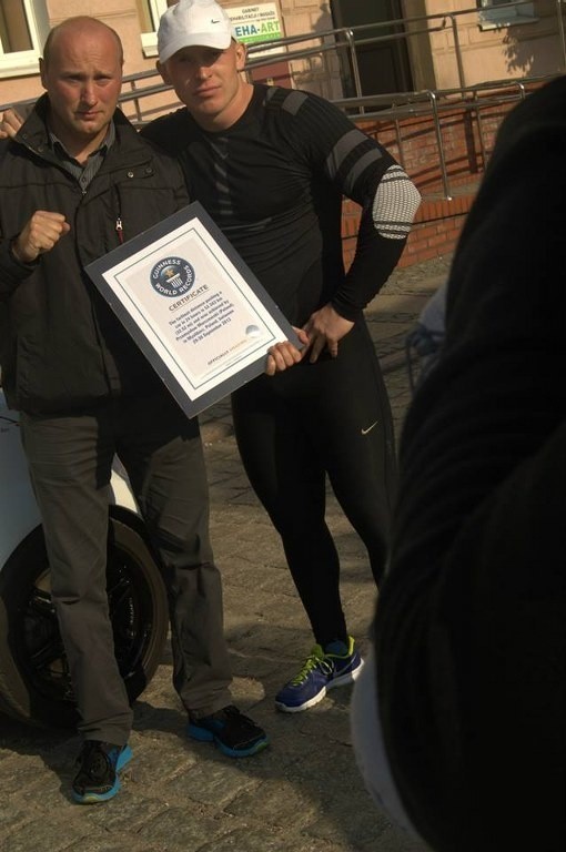 Przemysław Marczewski (z prawej) z certyfikatem Guinnessa potwierdzającym jego poprzedni rekord - w 2012 roku przepchnął auto na odległość ponad 50 km - oraz Robert Borkowski, organizator akcji.