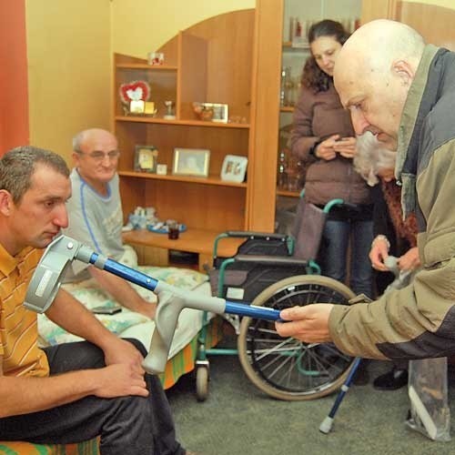 Mariusz i Mirosław Kaczmarkiewiczowie (siedzą na kanapie) otrzymali od Erika (pochylony na pierwszym planie) sprzęt rehabilitacyjny: wózek inwalidzki, windę do podnoszenia osób niepełnosprawnych i kule.