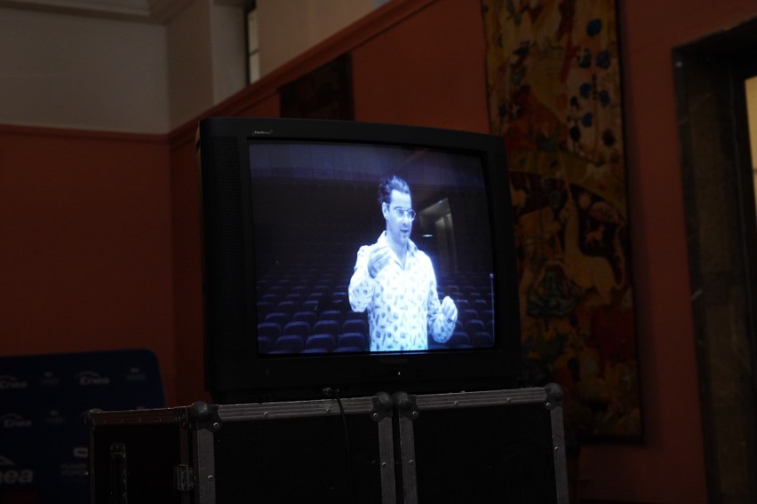Z ekranu monitora dyrygent Bassem Akiki poprowadzi chór w...