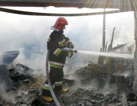 Strażak z Opatowa gasi pożar budynku gospodarczego w Brzozowej w gminie Tarłów.