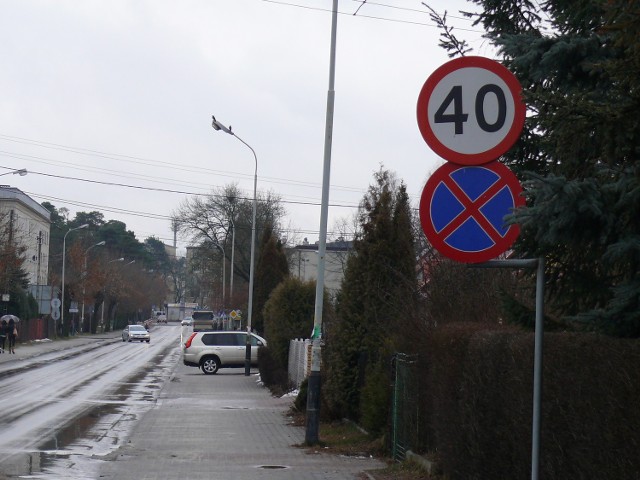 Zakaz zatrzymywania się i postoju na ulicy NIezłomnych, z dali widać auto wjeżdżające na posesję.