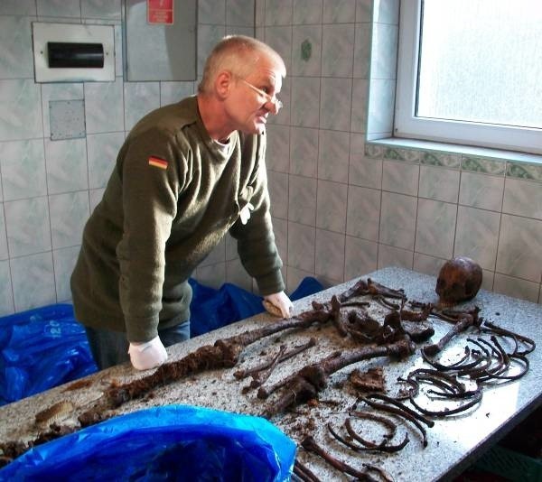 Harald Schroedter z Fundacji Przyjaźń podczas badania szczątków ekshumowanych spod śmietnika. Powyżej tabliczka z jednej z trumien.