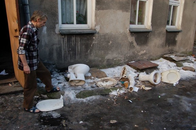 Andrzej Serej demonstruje ustępy wymontowane przez pracowników administracji z toalet na korytarzach, które leżą na podwórku. 