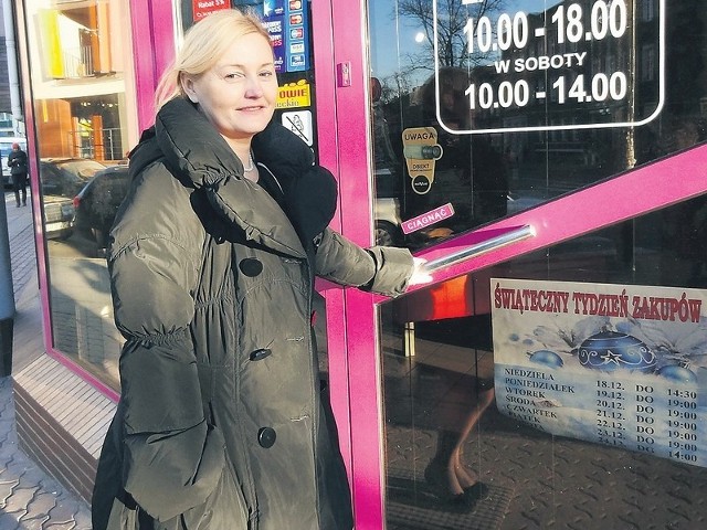 Elżbieta Dybowska przed swoim sklepem. Na drzwiach widnieje plakat akcji "Świąteczny Tydzień Zakupów&#8221;.