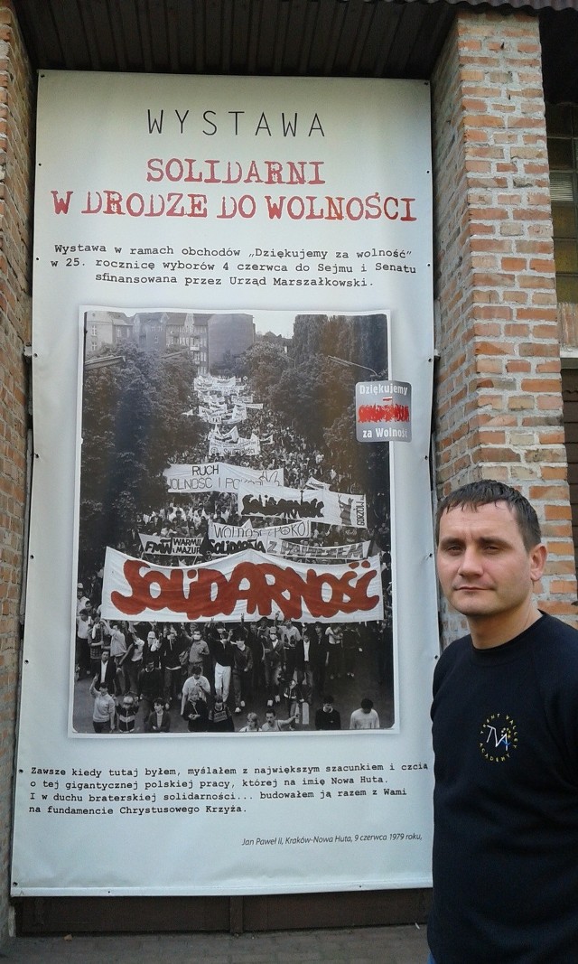 Andrzej Muzyka (36 l.) - zdjęcie z 3 października 2014 r. przy plakacie wystawy „Solidarni w drodze do Wolności”  prezentowanej w Krakowie-Nowej Hucie
