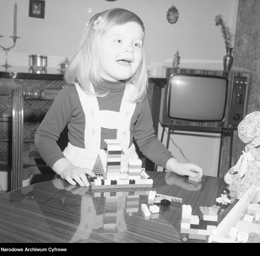 Ewa Spirydowicz bawi się klockami "Lego" przy stole. W tle...