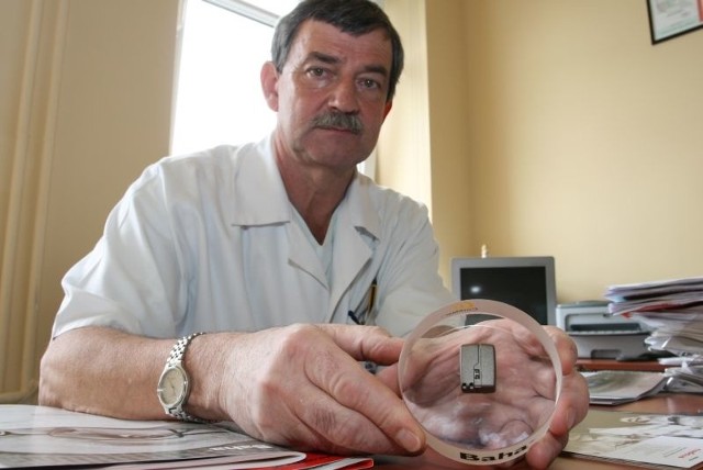 Doktor Tadeusz Mierzwa pokazuje procesor dźwięku, który jest niewiele większy od paznokcia.