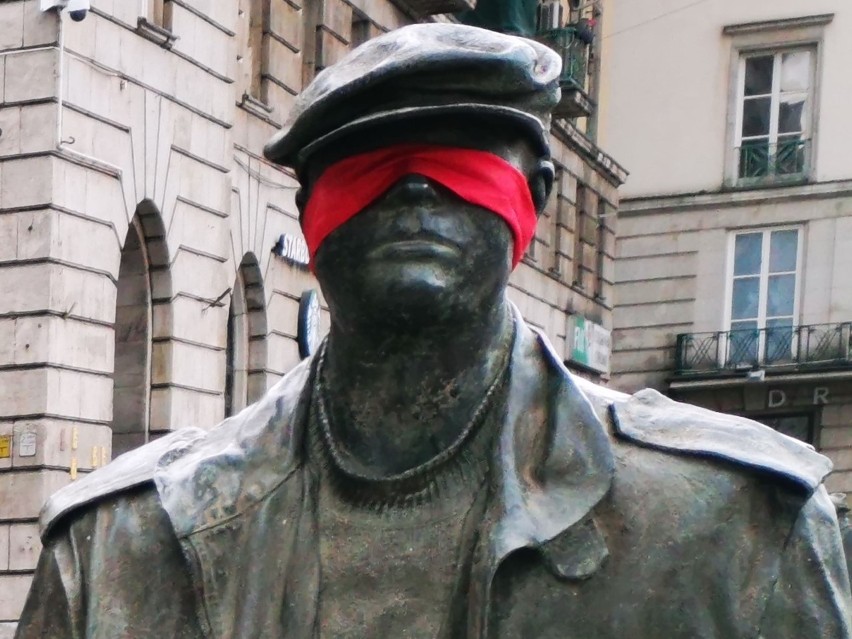 Czerwone opaski na figurach Pomnika Anonimowego Przechodnia...