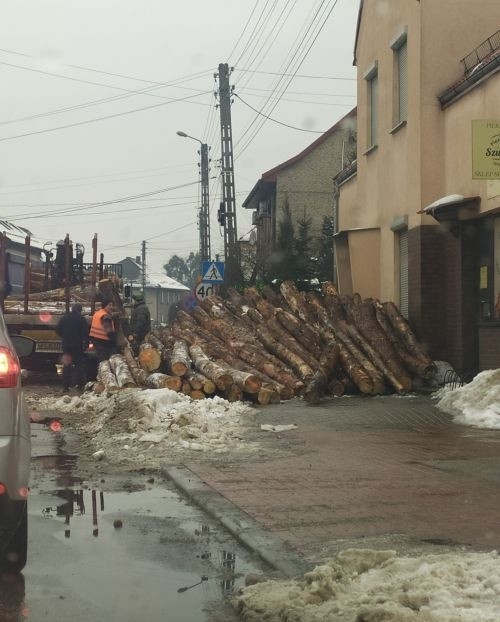 Wypadek w Rudach. Bale drewna spadły na ulice i chodnik....
