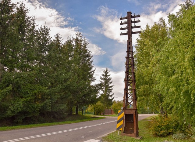 Zabytkowy słup telefoniczny z czasów Twierdzy Przemyśl stoi i niszczeje przy ruchliwej drodze.