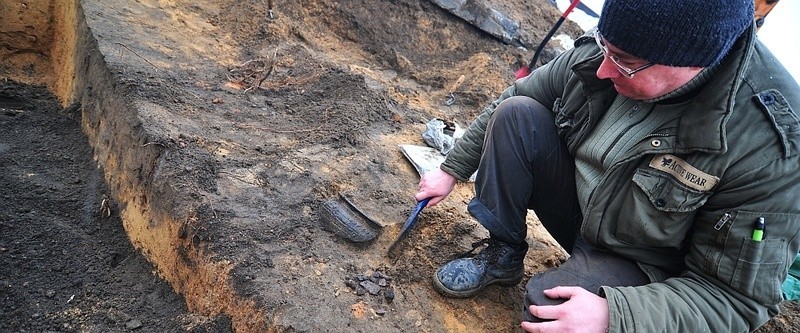 Archeolog powoli odsłania ceramikę w obiekcie, czyli w jamie...