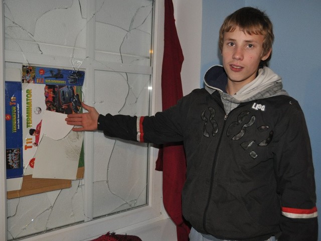 Adrian pokazuje wybite okno przez które do jego mieszkania dostał się złodziej. 