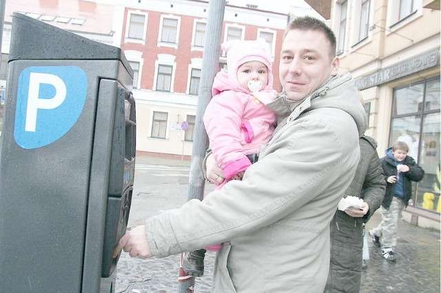 Łukasz Mikołajczak, z córką Marceliną, kupuje bilet w parkomacie na pl. Wolności