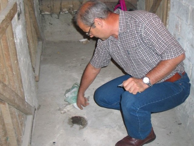 Zbigniew Jaśkiewicz, jeden z lokatorów, pokazuje dziurę, z której od czasu do czasu wypływają fekalia.