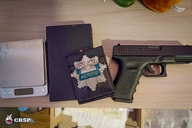 Przedmioty zabezpieczone podczas akcji - policyjna "blacha" i pistolet Glock