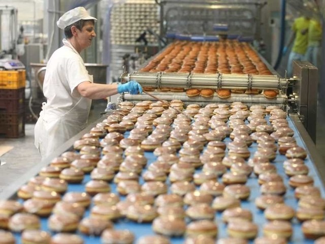 W Piekarni Pod Telegrafem od środy produkcja nastawiona była głównie na pączki. Na zdjęciu pracownik sprawdza pączki tuż po "kąpieli lukrowej&#8221;.