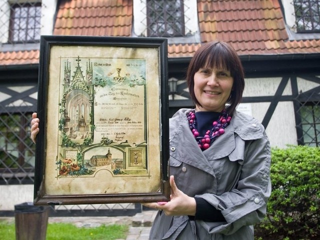 Dorota Ciecholewska ze słupskiego Muzeum Pomorza Środkowego prezentuje jeden z darów &#8211; pamiątkę konfirmacji z 1900 roku, na której widać kościół Mariacki.