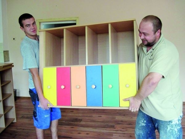 Konserwator z SP nr 10 w Łomży, Mariusz Gryszko (na zdjęciu z prawej) wraz z pomocnikiem wnoszą meble dla sześciolatków. Dzieci będą miały kolorowe ławki, krzesła i szafeczki na swoje rzeczy.