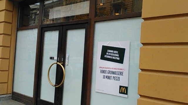 Na drzwiach wisi kartka zapraszająca do najbliższego otwartego McDonald'sa.