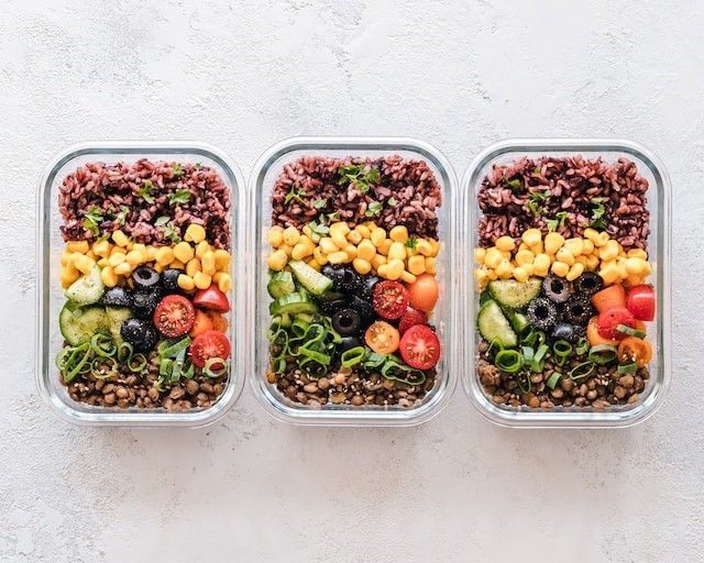 Widok z góry na trzy posiłki w pudełkach: kolorowe, pełne warzyw, zdrowo wyglądające dania.