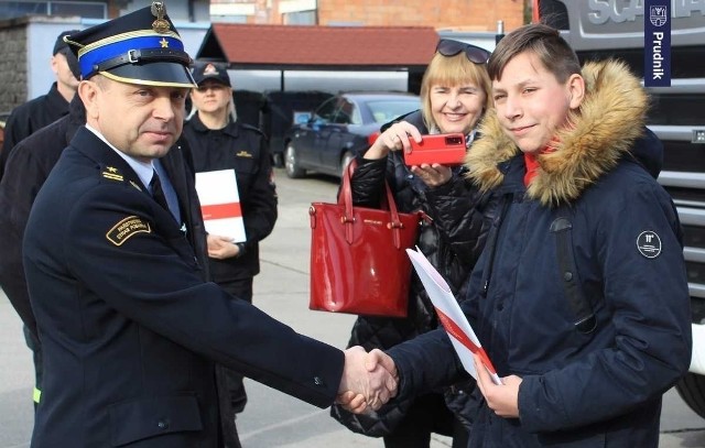 Dominik odbiera list gratulacyjny od komendanta powiatowego PSP w Prudniku