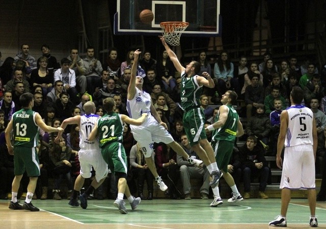 W efektownej akcji pod koszem gości Marcin Łakis. Próbuje go zablokować Michał Gabiński (nr 15). Z nr 21 w zielonej koszulce najlepszy zawodnik spotkania Paweł Kikowski