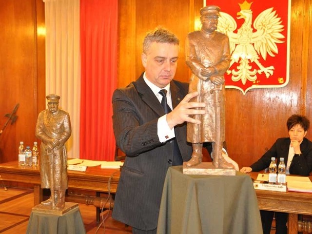 Wiceburmistrz Daniel Rak odsłania modele pomnika Józefa Piłsudskiego przygotowane w pracowni Wiesława Adamskiego.