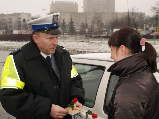 Młodszy aspirant Artur Putowski ze świętokrzyskiej drogówki wręcza kwiaty kierującej