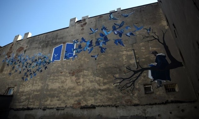 Mural przy ul. Zielonej przedstawia św. Dominika czytającego Biblię oraz ptaki przelatujące przez okno.