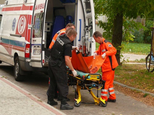 Policjanci pomagali sanitariuszom przenieść rannego mężczyznę do karetki pogotowia.