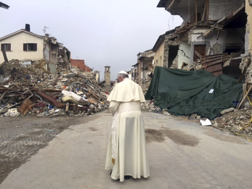 Papież Franciszek przechodzi między gruzami zawalonych domów...