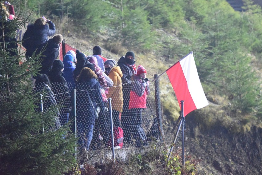 Skoki narciarskie w Wiśle. Ludzie kibicują zawodnikom zza ogrodzenia. Policja ostrzega przed mandatami