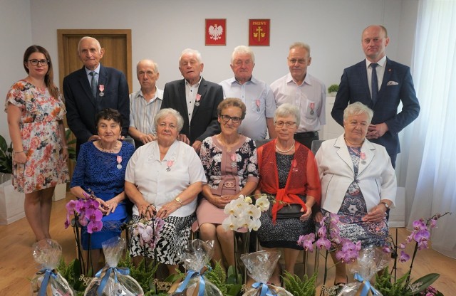 Zgodnie z tradycją lat ubiegłych również i w tym roku w gminie Pniewy odbyło się wręczenie medali za długoletnie pożycie małżeńskie. Tym razem ze względów bezpieczeństwa odbyły się dwie uroczystości - 30 lipca i 2 sierpnia.Ireneusz Szymczak, wójt gminy Pniewy wraz z Renatą Wojtczak, kierownikiem Urzędu Stanu Cywilnego gościli dostojnych Jubilatów w Sali Ślubów Urzędu Stanu Cywilnego w Pniewach, dokonali aktu dekoracji oraz złożyli serdeczne podziękowania, gratulacje i życzenia dalszego szczęśliwego pożycia małżeńskiego.Medale te to specjalne odznaczenie przyznawane przez Prezydenta RP doceniające zgodność pożycia małżeńskiego, trud pracy i wyrzeczeń dla dobra założonej przed pół wiekiem rodziny. Wspólnie przeżyte pół wieku stanowi świadectwo wzajemnej dojrzałej miłości, a także doskonały przykład dla obecnych i przyszłych pokoleń w jaki sposób budować więzy rodzinne i pielęgnować miłość.- Gratuluję państwu tego wyróżnienia jak też tak pięknego jubileuszu i życzę wielu kolejnych lat przeżytych w zdrowiu, miłości i wzajemnym szacunku, życzę radości z każdego kolejnego dnia i wszelkiej pomyślności, byśmy mogli świętować kolejne jubileusze, bo tylko „Ludzie, którzy kochają się z całego serca nigdy się nie starzeją…” - mówiła Renata Wojtczak.Wójt Ireneusz Szymczak podkreślił, że jest to dla niego wielki zaszczyt, iż może tak dostojnych jubilatów gościć w swoich progach. Wyraził wielki szacunek dla trwałości małżeństwa. Rocznica ta to szczególna okazja, aby się zatrzymać i spojrzeć wstecz na to co osiągnęliście w ciągu wspólnego życia.- W tym czasie zmienił się otaczający Was świat, nastawały nowe rządy, przemijały ustroje polityczne, w końcu zmienił się wiek… a Państwo nadal jesteście razem - mówił Wójt Ireneusz Szymczak. Na koniec życzył Jubilatom szczęścia, spokoju, dużo zdrowia i pomyślności na kolejne lata.Złote Gody obchodziły następujące pary małżeńskie: Danuta i Tadeusz Arak, Bożenna i Sylwester Wojtczak, Teresa i Kazimierz Wojciechowscy, Hanna i Janusz Pelkanowscy, Krystyna i Tadeusz Grzeszczyk, Ewa i Andrzej Rusieccy, Teresa i Marek Domasiewicz, Michalina i Józef Czerniawscy świętujący 53 rocznicę ślubu oraz Elżbieta i Henryk Praga świętujący 60 rocznicę.