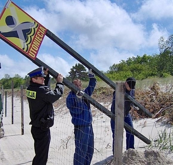 Na zdjęciu kierownik posterunku policji w Dziwnowie asp. sztab. Jarosław Kapitan razem z pracownikami urzędu morskiego wkopują tablicę na dzikim kąpielisku.