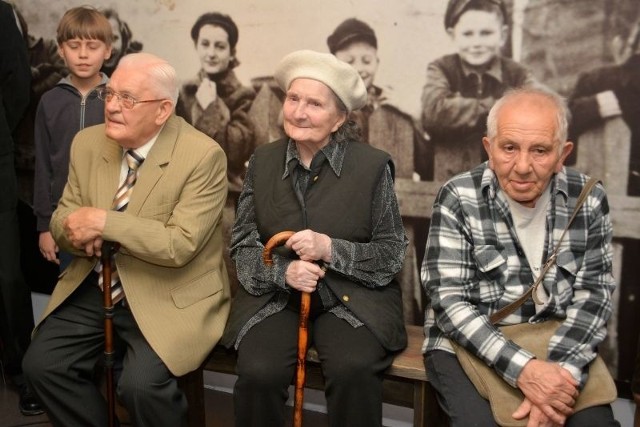 Wiera Kalisz z innymi bojarczykami na tle starej fotografii mieszkańców dzielnicy. Wśród nich młoda Wiera Kalisz