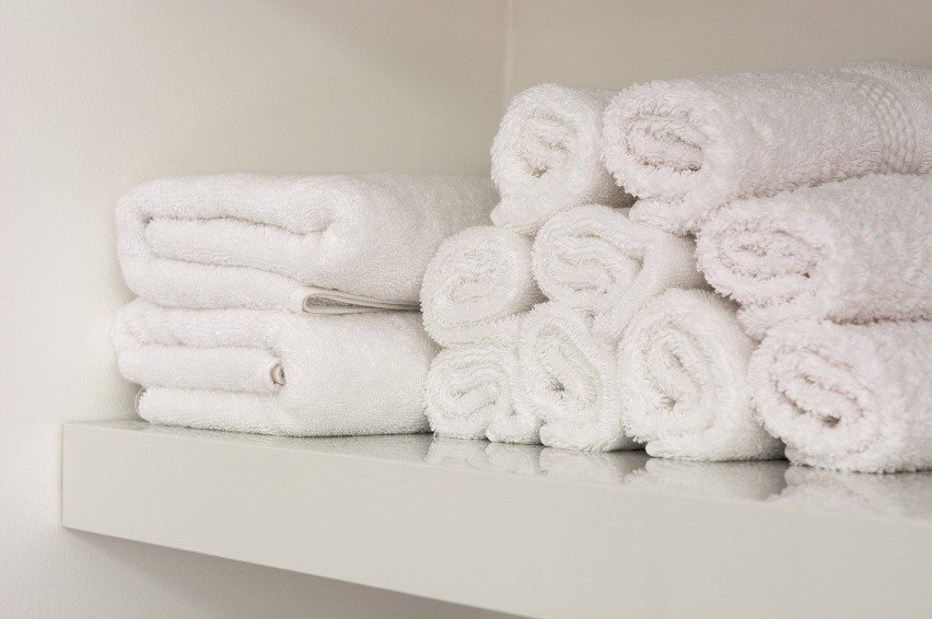 Ręczniki trzymane w łazience, w której powietrze jest...