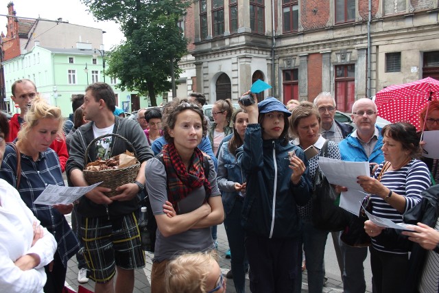 Uczestnicy wycieczki piekarnianym szlakiem oglądają stare zdjęcia i konsumują berliński chleb przed dawną piekarnią i cukiernią przy ul. Sienkiewicza 16