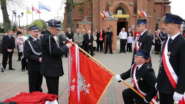 Andrzej Szczych, prezes Zarządu Powiatowego Związku Ochotniczych Straży Pożarnych Rzeczypospolitej Polskiej, dekoruje sztandar OSP z Wrzosu. Z lewej - Mirosław Slifirczyk, starosta radomski i wiceprezes Zarządu Powiatowego Związku Ochotniczych Straży Pożarnych Rzeczypospolitej Polskiej.