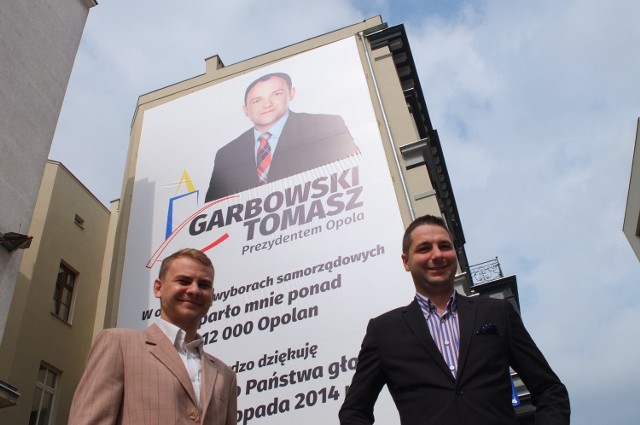 Marcin Rol i Patryk Jaki pod plakatem Tomasz Garbowskiego na ulicy Krakowskiej.