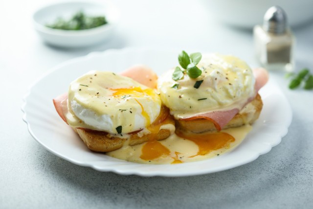 Klasyczne jajka po benedyktyńsku to danie złożone z jajek w koszulce, sosu holenderskiego i chrupiących grzanek.